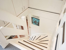 Una escalera blanca con un cartel de 'The Beat Around the Bush' en la pared.