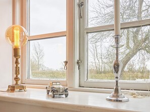 A window with a view of trees, a small toy car, and a lamp on the windowsill.