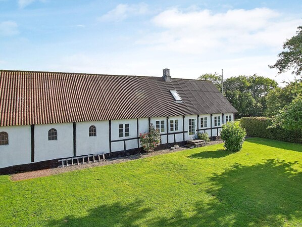 A traditional half-timbered house with a sloped roof, a small garden, and a clear sky.