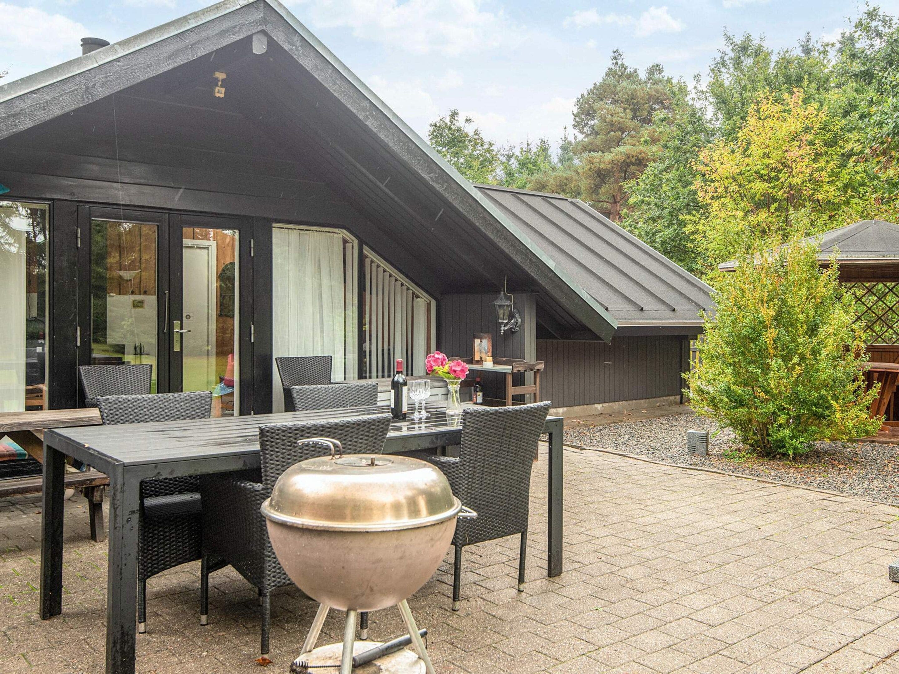 Eine Terrasse mit Grill, Esstisch und Stühlen.