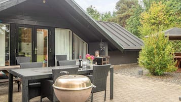 Eine Terrasse mit Grill, Esstisch und Stühlen.
