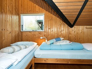 A room with two wooden bunk beds, a window with a view of trees, and a white lamp on the wall. - 6 Person Holiday Home in Farvang (Farvang)