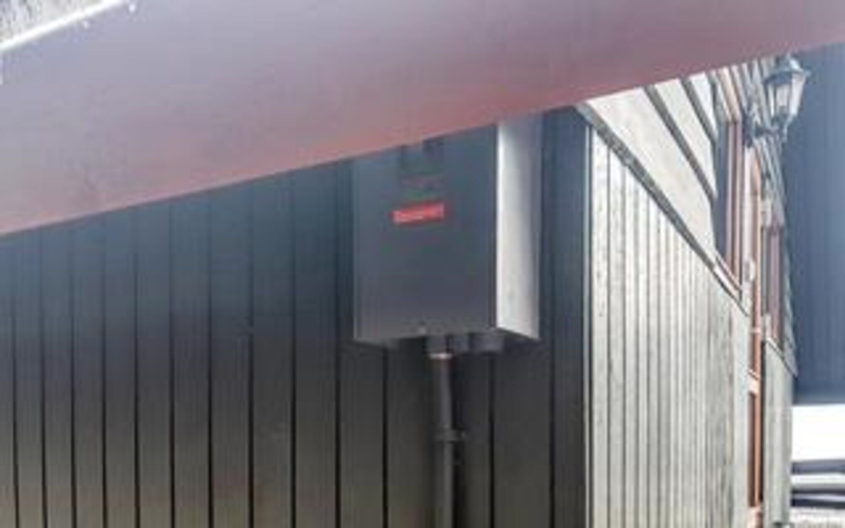 A building with a metal exterior and a red sign on a utility box.