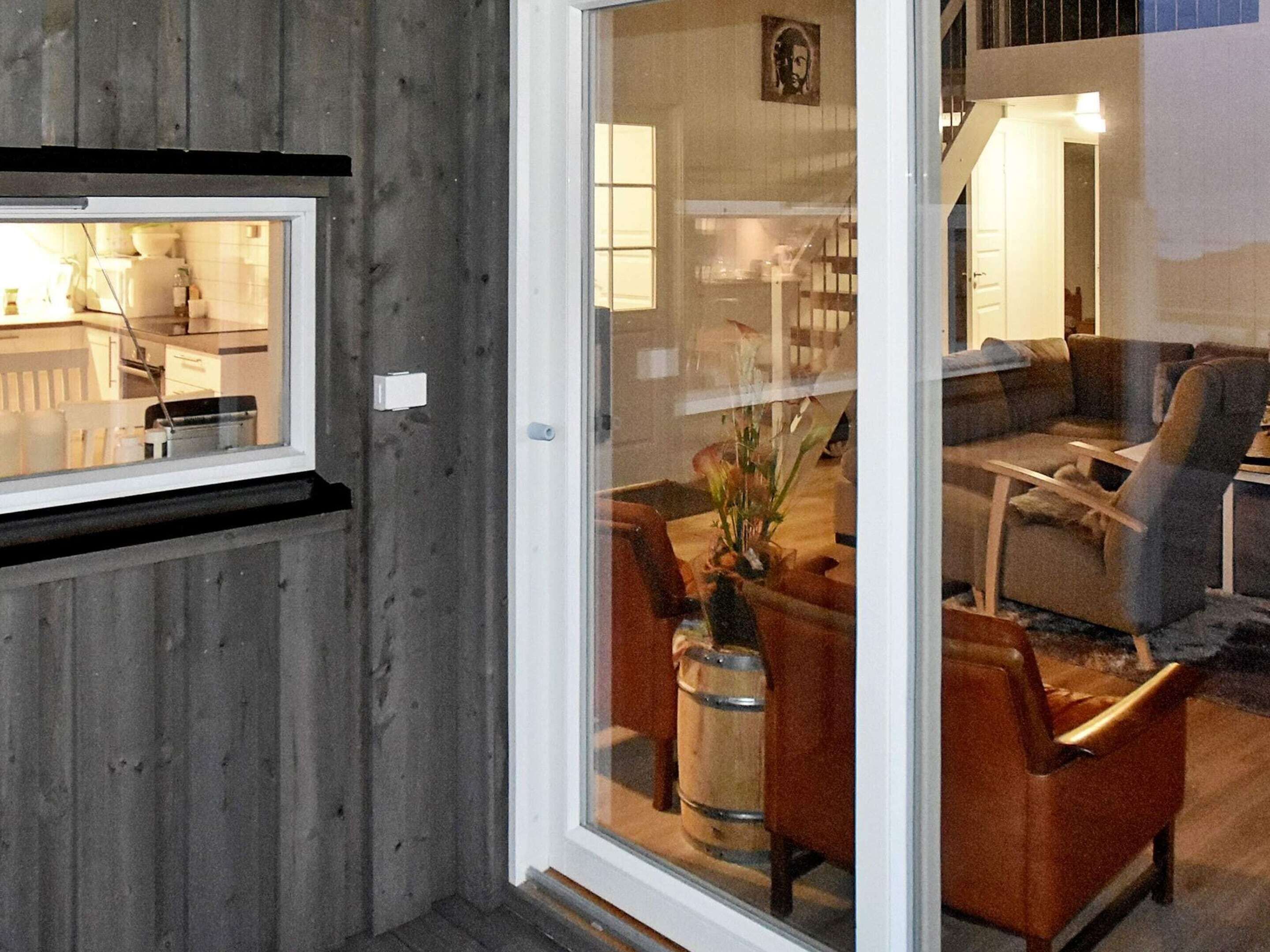 A room with a wooden wall, a window, a door, a sofa, a chair, and a table.