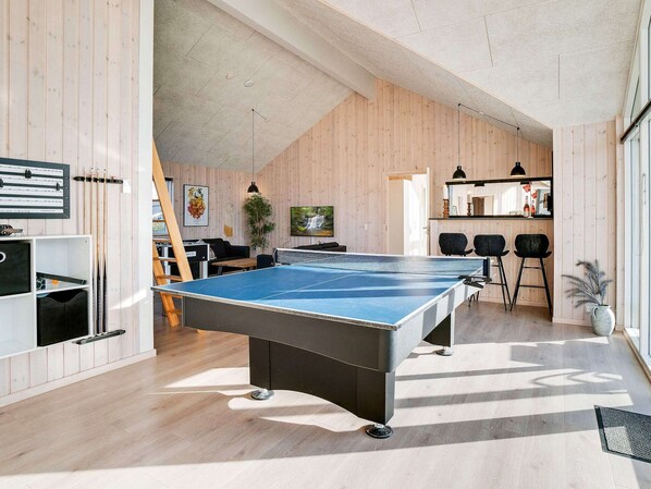 A ping pong table in a room with wooden walls and a sloped ceiling.