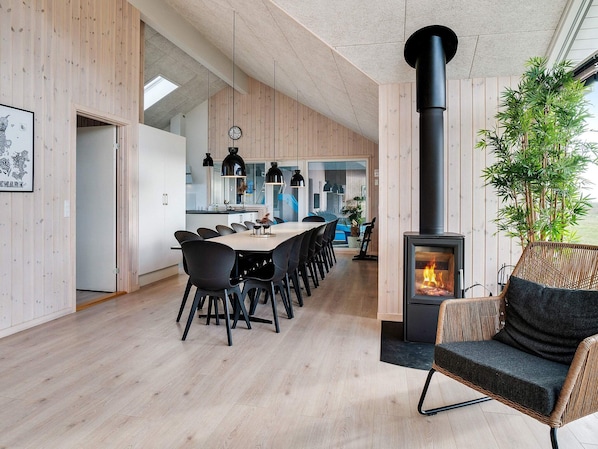 A modern interior with a dining area, a black stove, and a wicker chair.