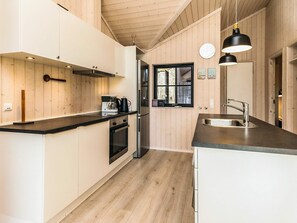 Cozinha moderna com painéis de madeira, forno embutido, cafeteira e janela com vista.