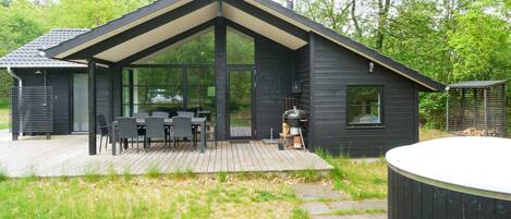 Une maison moderne dotée d’une terrasse, d’un barbecue et d’un jacuzzi.