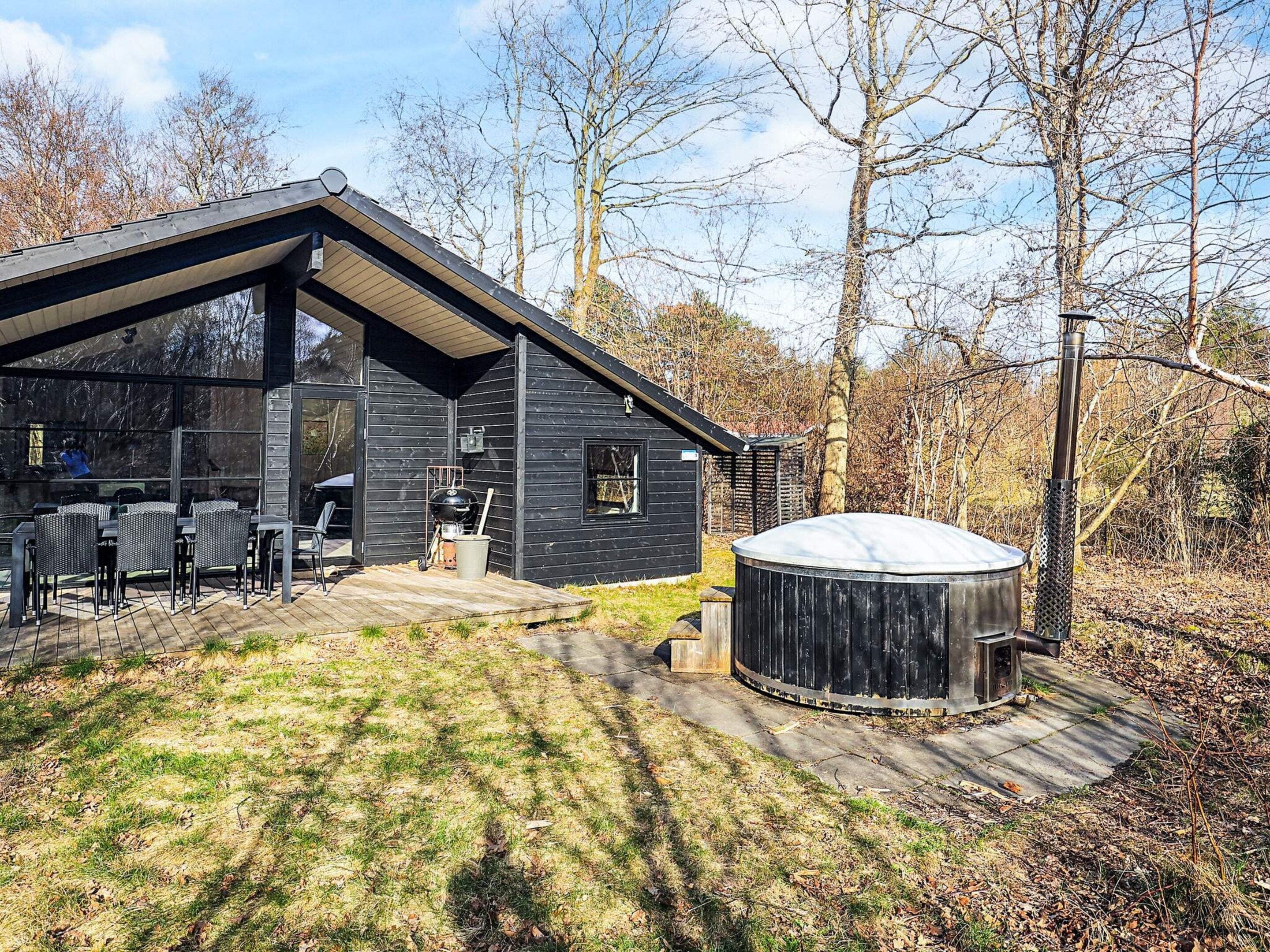 Una cabaña moderna con un patio, un jacuzzi y una terraza.