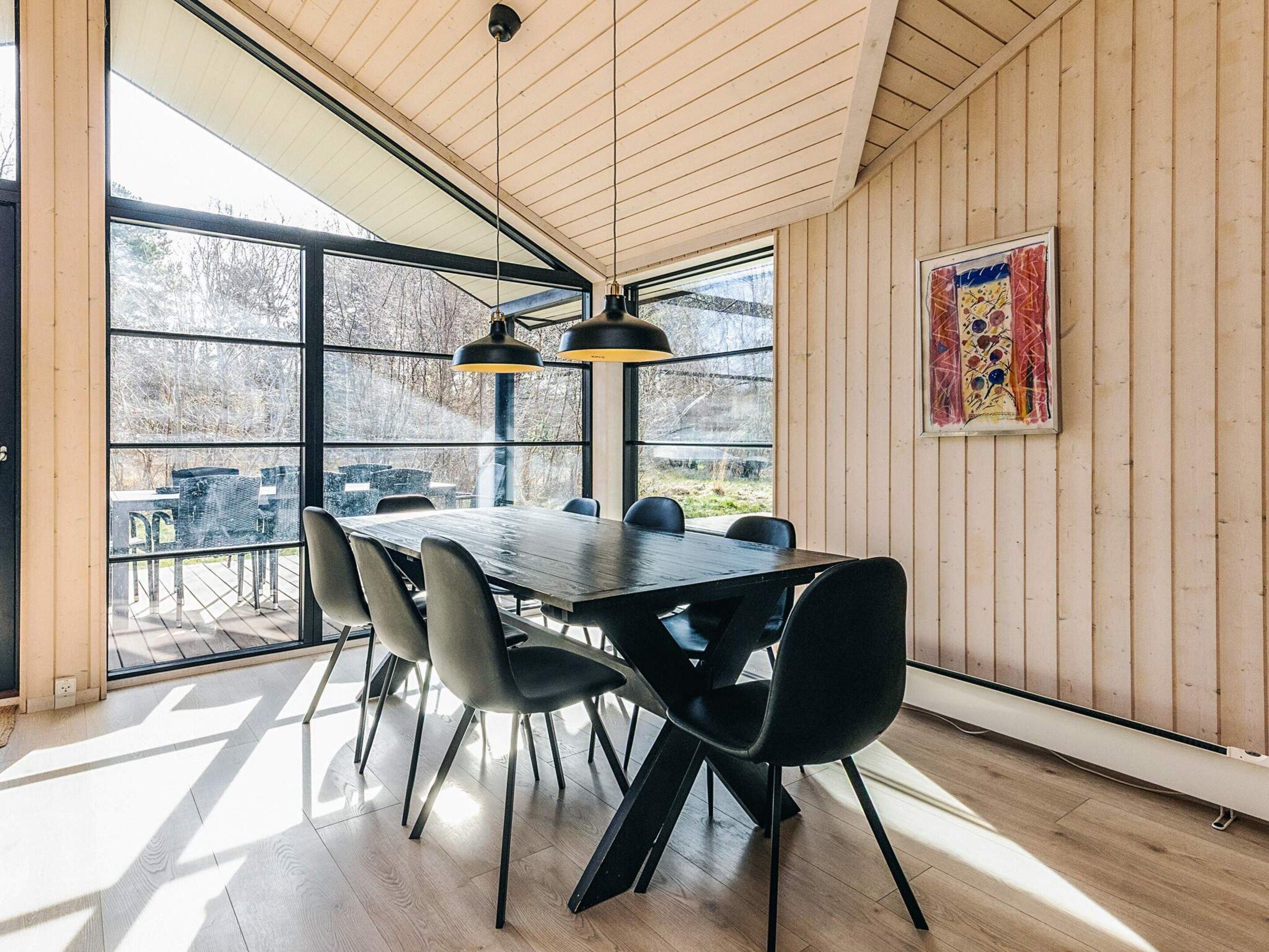 Een eetgedeelte met een grote tafel, zwarte stoelen en hanglampen.