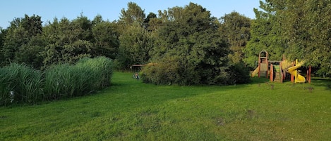 Un espace vert avec une aire de jeux comprenant un toboggan et des structures d’escalade.