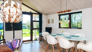A modern dining area with a round table, white chairs, and a hanging light fixture. - 4 Star Holiday Home in Romo (Rømø)