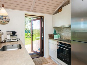 A modern kitchen with a large stainless steel refrigerator, a built-in oven, and a coffee machine.