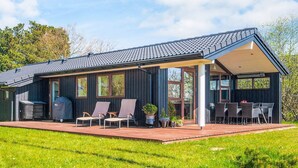 A modern house with a covered patio, large windows, and a well-maintained lawn. - 4 Star Holiday Home in Romo (Rømø)