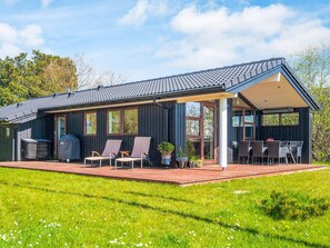 A modern house with a covered patio, outdoor seating, and a barbecue grill.