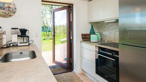 A modern kitchen with a stainless steel refrigerator, a built-in oven, and a coffee maker on the counter. - 4 Star Holiday Home in Romo (Rømø)