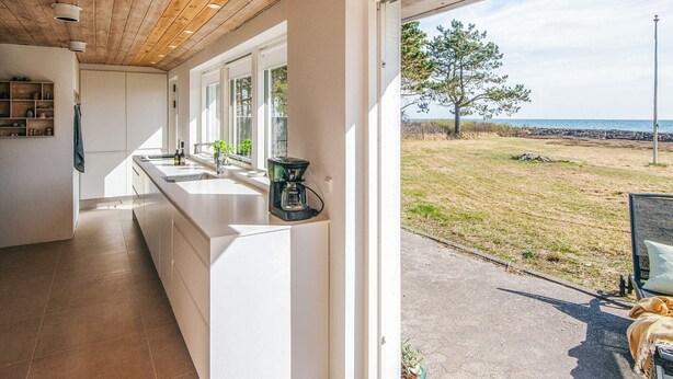 A modern kitchen with a long counter, built-in cabinets, and a coffee maker. - 12 Person Holiday Home in Ebeltoft (Ebeltoft)