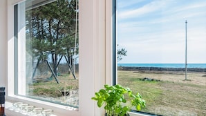 A window with a view of a beach and a grassy area with trees. - 12 Person Holiday Home in Ebeltoft (Ebeltoft)