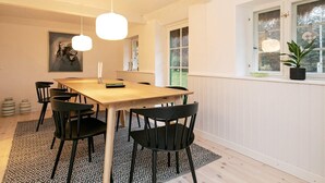A dining area with a wooden table and black chairs, a patterned rug, and pendant lights. - 5 Star Holiday Home in Laeso (Læsø)