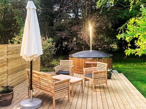 A wooden deck with a hot tub, wooden chairs, a table, and an umbrella. - 5 Star Holiday Home in Laeso (Læsø)