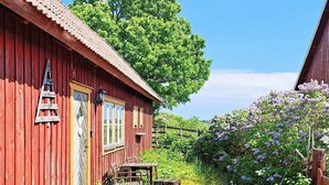 Ein rotes Holzhaus mit einer Veranda, einer Leiter und einem Tisch mit Stühlen davor.