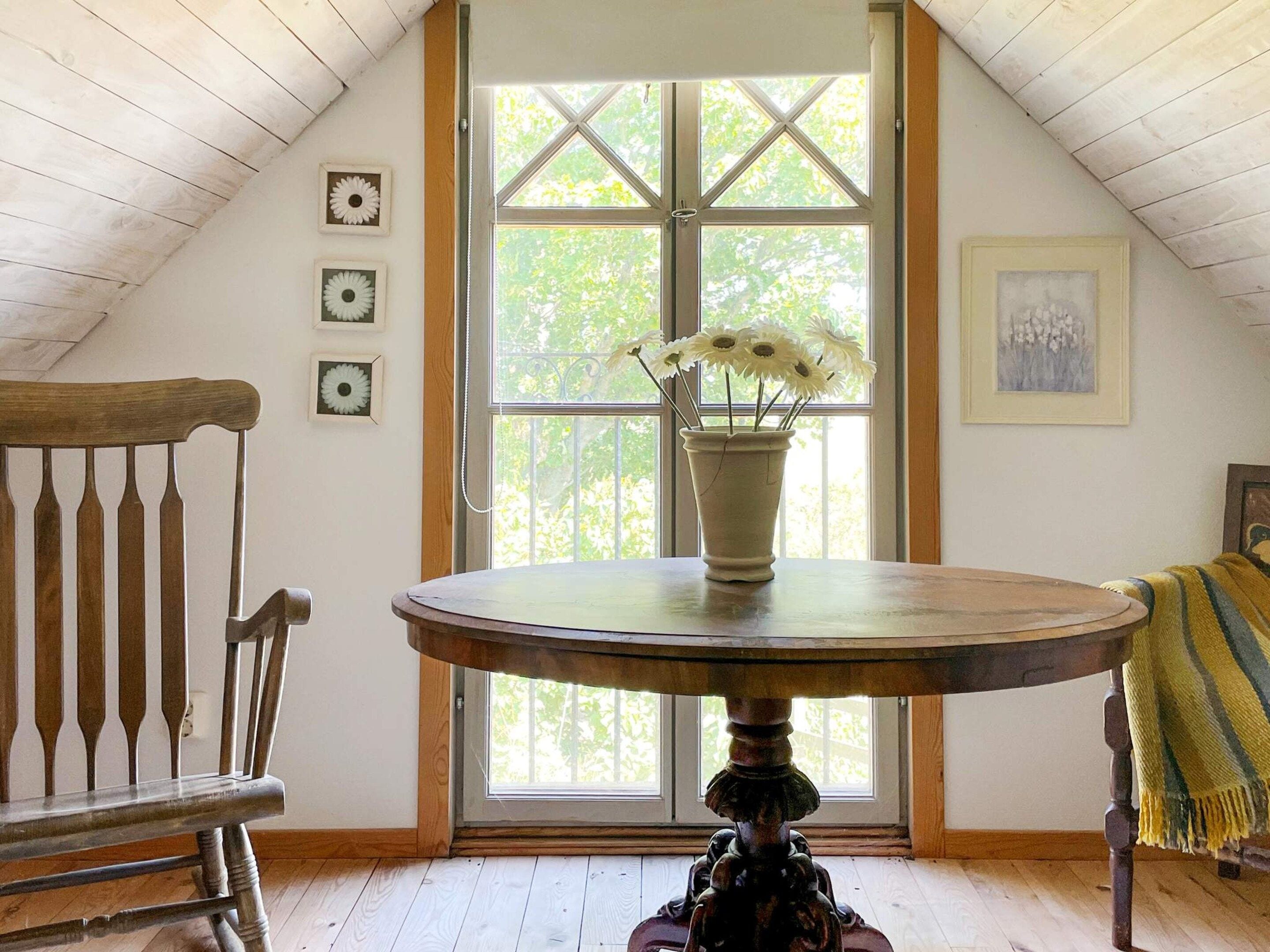 A room with a wooden table, a bench, and a window with a view of trees.