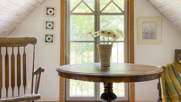 A room with a wooden table, a bench, and a window with a view of trees.