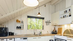 A modern kitchen with white cabinetry, a large window, and a hanging pendant light. - 6 Person Holiday Home in Tranekaer (Tranekaer)