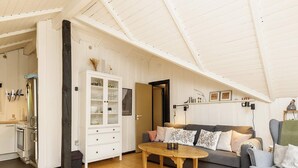 A spacious living area with a high ceiling, a wooden dining table, a grey sofa, and a white cabinet with glass doors. - 6 Person Holiday Home in Tranekaer (Tranekaer)