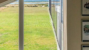 A room with a large window offering a view of a well-maintained lawn and distant hills. - 5 Star Holiday Home in Ebeltoft (Ebeltoft)
