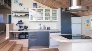 A modern kitchen with wooden flooring, a built-in oven, a coffee machine, and a dishwasher. - 5 Star Holiday Home in Ebeltoft (Ebeltoft)