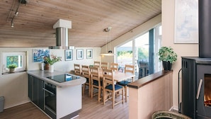 A modern kitchen with wooden flooring, a central island, and a dining area with chairs. - 5 Star Holiday Home in Ebeltoft (Ebeltoft)