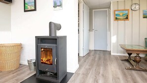 Moderni olohuone, jossa on puukamiina, rottinkikori ja ruokapöytä tuoleineen.