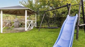 En have med gyngestativ, rutschebane, overdækket siddeområde og gummigynge.
