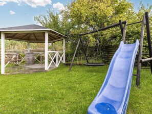A backyard with a wooden swing set, a slide, a covered seating area, and a tire swing. - 4 Star Holiday Home in Albaek (Aalbaek)