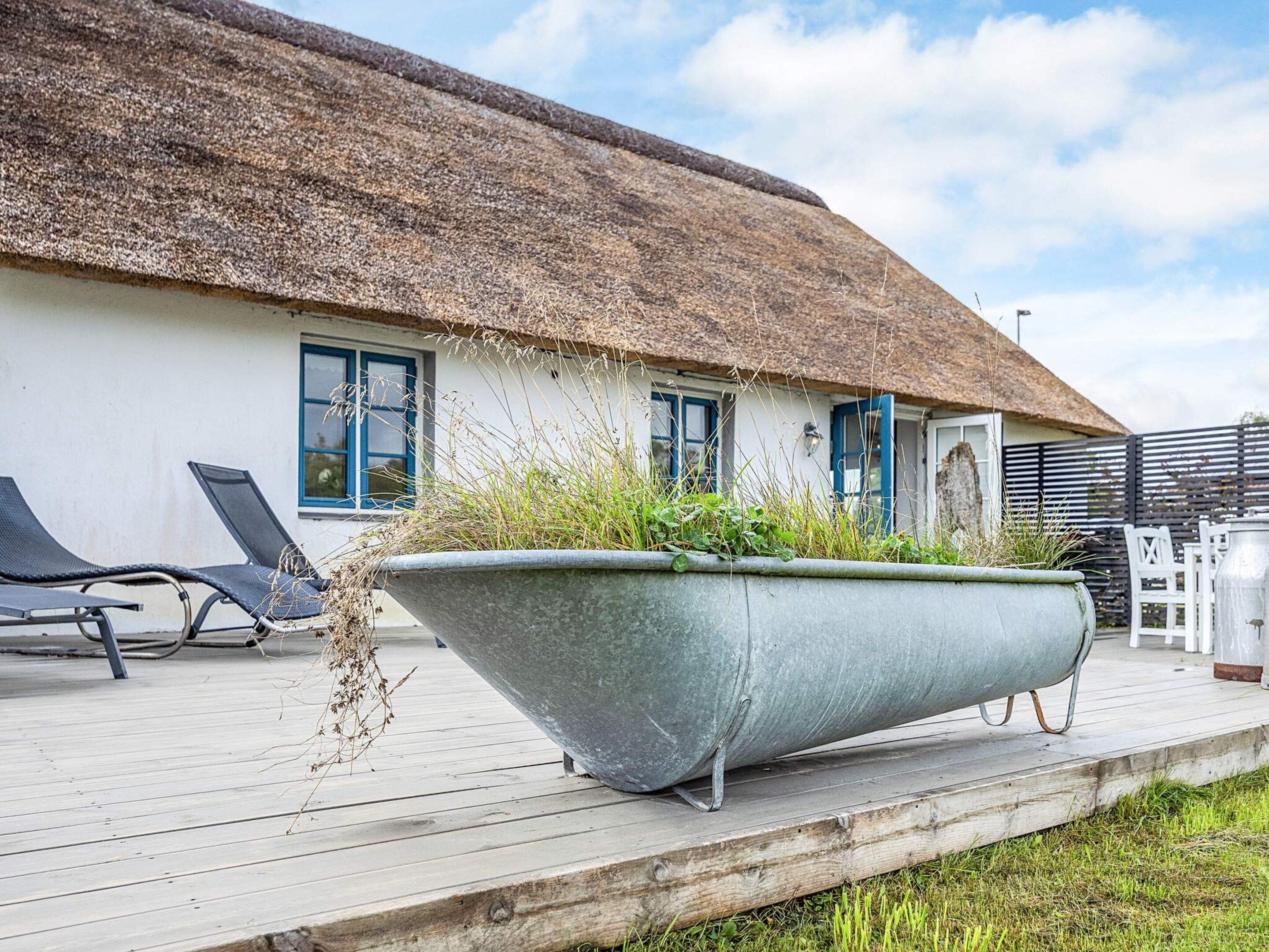 A thatched-roof building with a large planter on the deck.