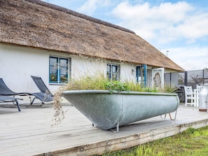 Un bâtiment à toit de chaume avec un grand jardon sur la terrasse.