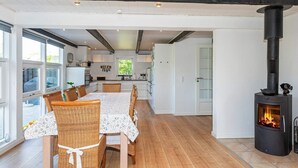 A modern kitchen with a central island, wooden flooring, and a built-in wood stove.