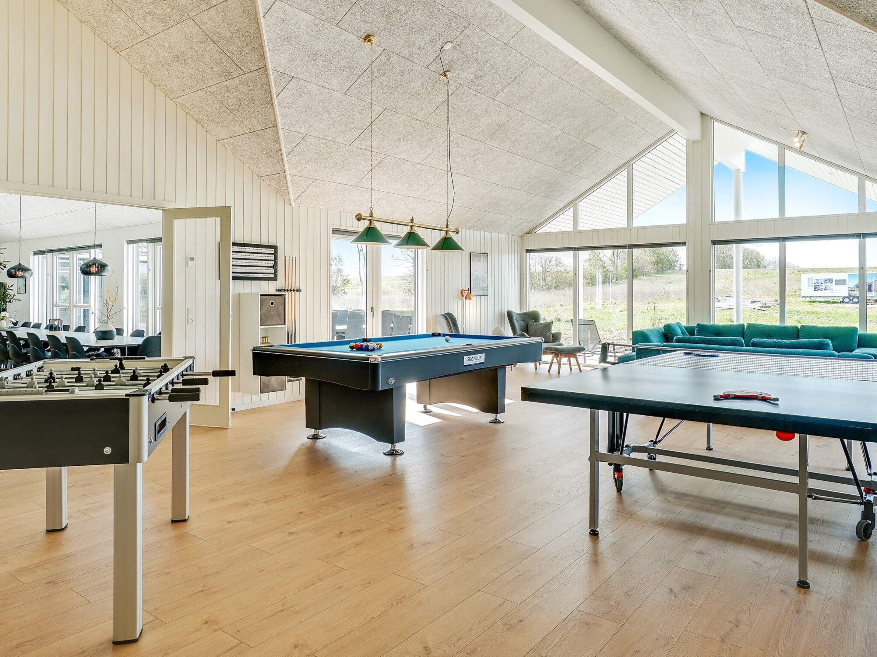 A spacious indoor recreational area with a foosball table, pool table, and billiards table.
