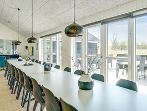 A long dining table with chairs, pendant lights, and a vase with branches. - 5 Star Holiday Home in Grenaa (Grenaa)