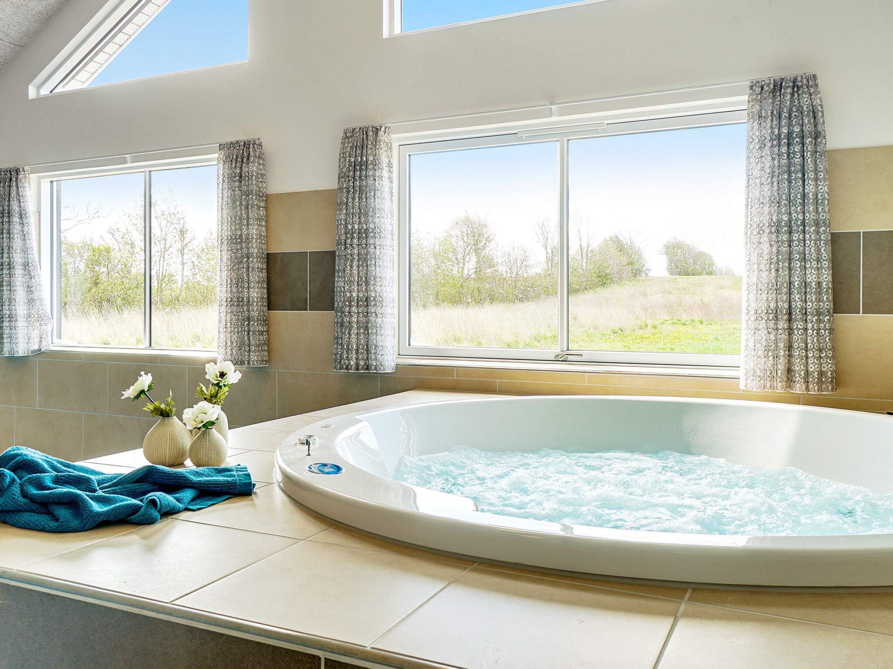 A bathroom with a hot tub, large windows, and a view of the outdoors.