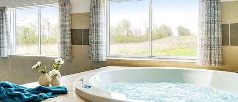 A bathroom with a hot tub, large windows, and a view of the outdoors.