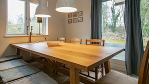 A dining area with a wooden table, benches, and pendant lights.
