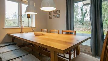 A dining area with a wooden table, four chairs, and two pendant lights.