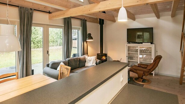 A cozy interior with a wooden ceiling, a sofa, a dining table, a TV, and a fireplace.