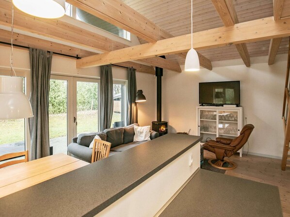 A cozy interior with a wooden ceiling, a sofa, a dining table, a TV, and a fireplace. - 5 Person Holiday Home in Millinge (Millinge)