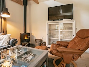 Uma sala de estar acolhedora com lareira, televisão e uma poltrona de couro confortável.