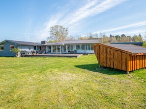 A modern house with a large deck and a wooden shed.