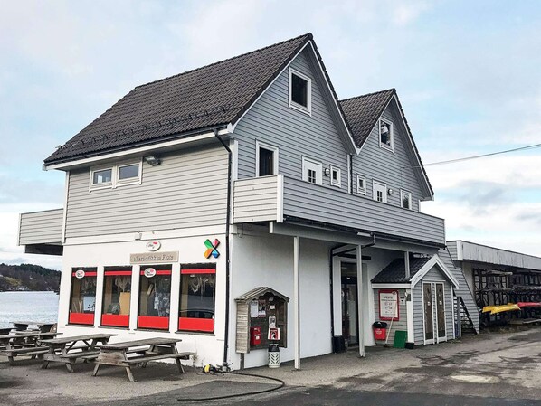 A two-story building with a balcony, a small attached structure, and a sign indicating a festival. - 6 Person Holiday Home in Seim (Alver)