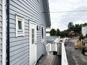 A house with a wooden deck, a garage door, and a view of a road and trees. - 6 Person Holiday Home in Seim (Alver)